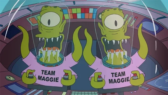 The Simpsons'ın ikonik uzaylı karakterleri Kang ve Kodos, uzay gemilerinin içinde 'Team Maggie' yazılı pembe tişörtler giymiş halde. Tek gözlü, yeşil renkli uzaylılar sivri dişlerini göstererek kameraya bakıyor.