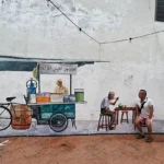 Malakka: Kuala Lumpur’un Ötesinde, Tarihle İç İçe Bir Durak Malakka’da bir sokak duvarında yer alan seyyar satıcı temalı duvar resmi önünde oturan bir ziyaretçi