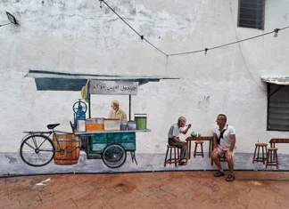 Malakka: Kuala Lumpur’un Ötesinde, Tarihle İç İçe Bir Durak Malakka’da bir sokak duvarında yer alan seyyar satıcı temalı duvar resmi önünde oturan bir ziyaretçi